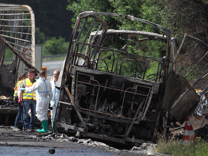 Bomberos y rescatistas trabajan junto a un autobús quemado en la autopista A9 cerca de Muenchberg, Alemania, el lunes 3 de julio de 2017 después de que el vehículo chocara con un camión y se incendiara. (Nicolas Armer/dpa vía AP)