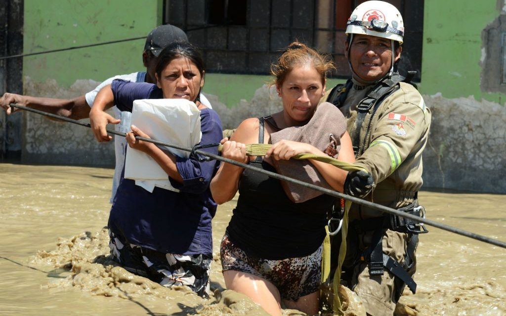 Rescuers help local residents of the town of Huarmey, 300 kilometres north of Lima, wade through muddy water in the street on March 19, 2017 after a flash flood hit the evening before.
The El Nino climate phenomenon is causing muddy rivers to overflow along the entire Peruvian coast, isolating communities and neighbourhoods. Thousands have been affected since January, and 72 people have died. Most cities face water shortages as water lines have been compromised by mud and debris. / AFP PHOTO / CRIS BOURONCLE        (Photo credit should read CRIS BOURONCLE/AFP/Getty Images)