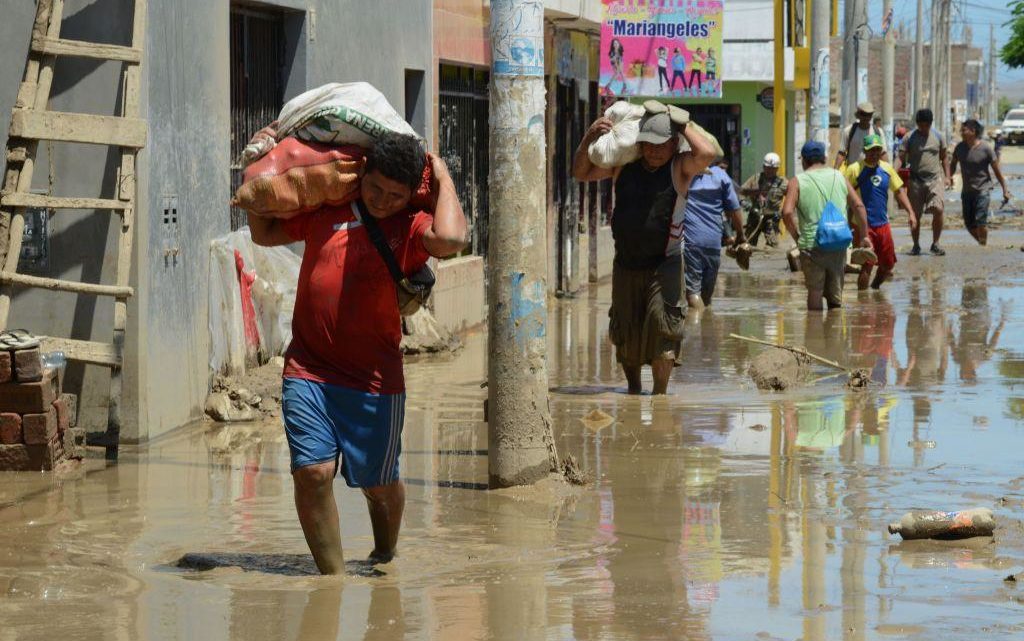 Local residents of the town of Huarmey, 300 kilometres north of Lima, wade through muddy water in the street on March 19, 2017 after a flash flood hit the evening before.
The El Nino climate phenomenon is causing muddy rivers to overflow along the entire Peruvian coast, isolating communities and neighbourhoods. Thousands have been affected since January, and 72 people have died. Most cities face water shortages as water lines have been compromised by mud and debris. / AFP PHOTO / CRIS BOURONCLE        (Photo credit should read CRIS BOURONCLE/AFP/Getty Images)